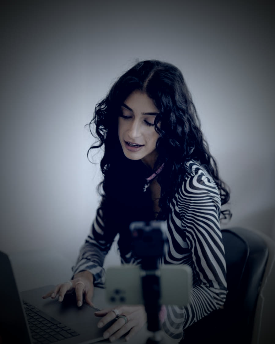 Criadora de conteúdo gravando vídeo com celular em tripé e notebook